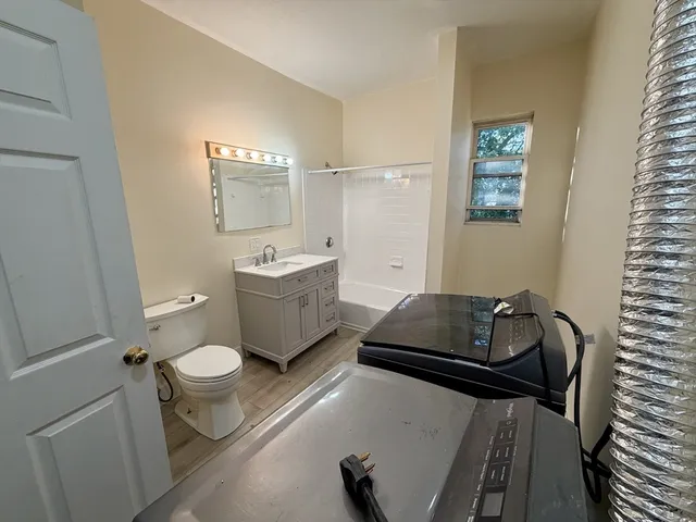 a bathroom with a granite countertop sink mirror vanity and toilet