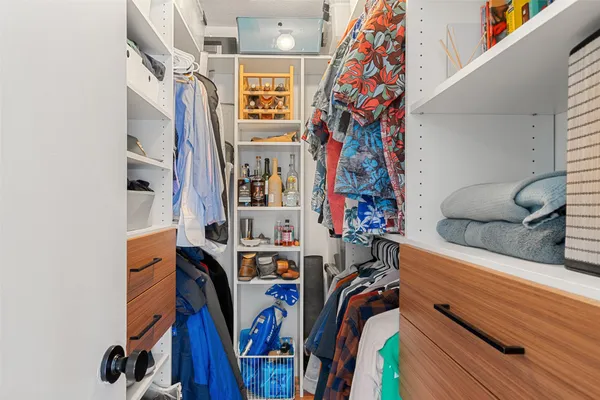 a view of walk in closet with clothes and shoes