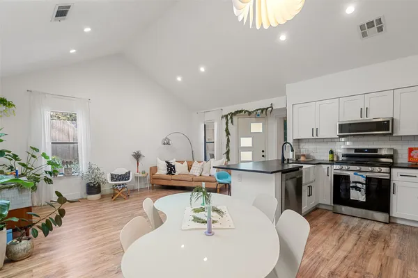 a living room with stainless steel appliances kitchen island granite countertop furniture a rug kitchen view and a potted plant