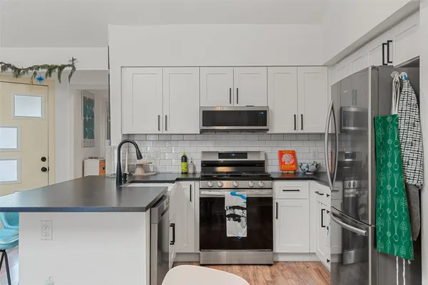 a kitchen with stainless steel appliances a sink a stove a refrigerator a sink a counter space and cabinets