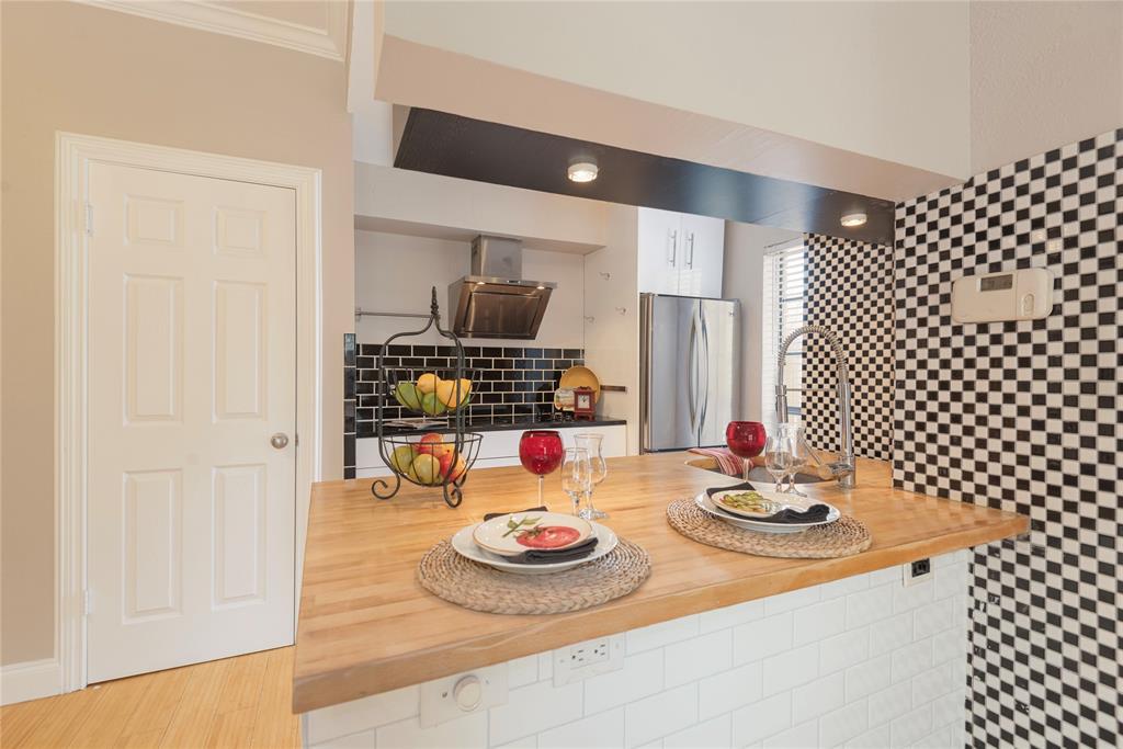 14333 Preston Road, Unit 2807 Dallas, TX 75254 - Photo 16 of 31 Kitchen with butcher block countertops, freestanding refrigerator, exhaust hood, white cabinetry, and ornamental molding