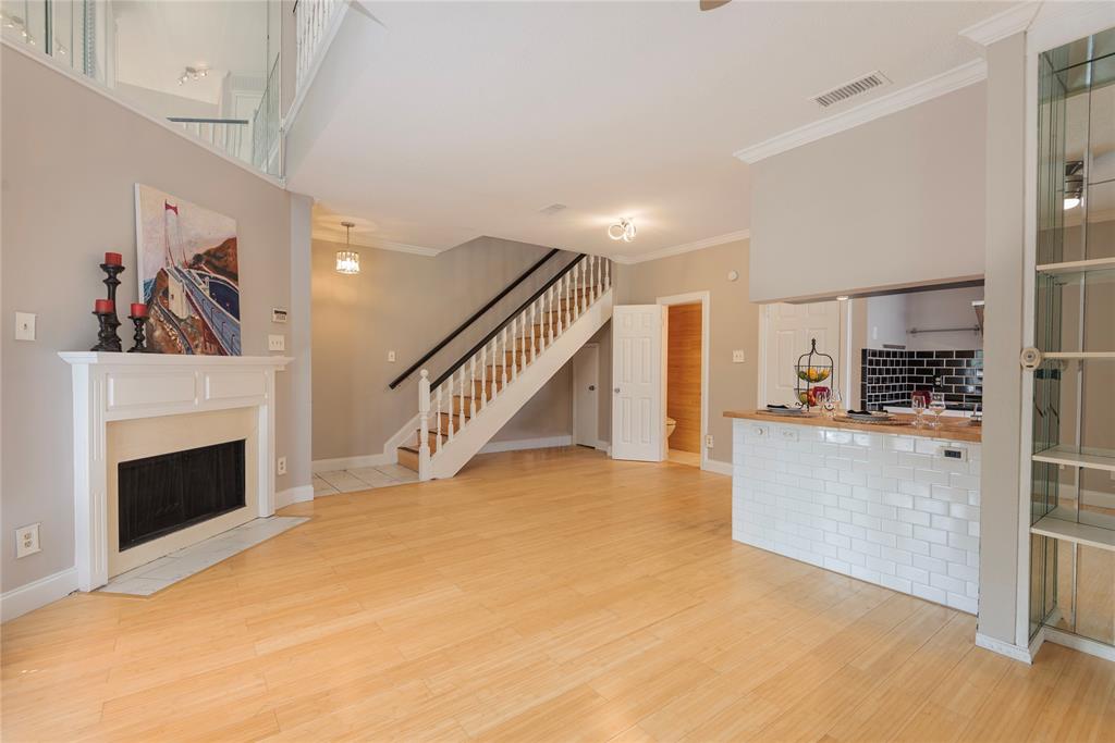 14333 Preston Road, Unit 2807 Dallas, TX 75254 - Photo 6 of 31 Unfurnished living room featuring a fireplace with flush hearth, stairway, crown molding, and wood finished floors