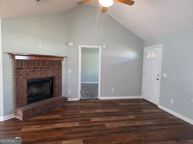 a view of empty room with wooden floor and fireplace
