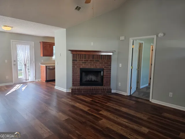 an empty room with wooden floor fireplace and windows