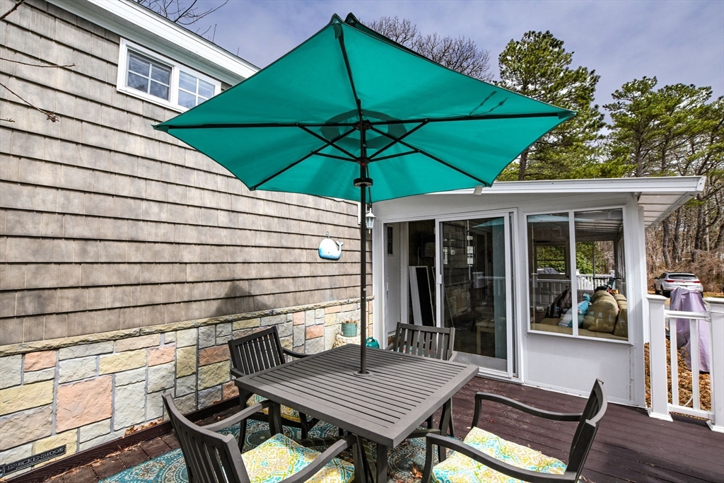 185 Cotuit Road, Unit 1 JUNIPER Sandwich, MA 02563 - Photo 3 of 20 a view of a patio with a table and chairs under an umbrella