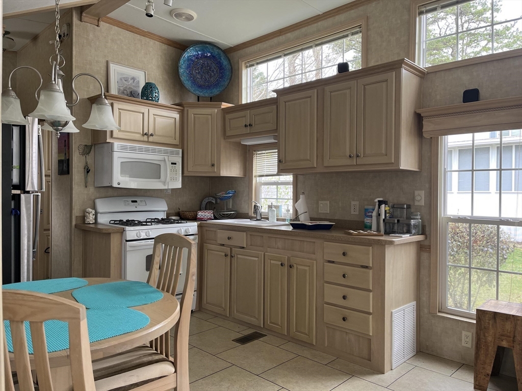 185 Cotuit Road, Unit 1 JUNIPER Sandwich, MA 02563 - Photo 6 of 11 a kitchen with stainless steel appliances granite countertop a stove a sink dishwasher and cabinets with wooden floor