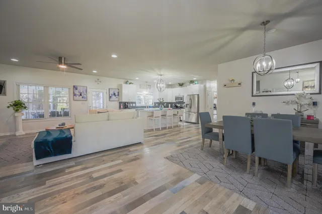 a living room with stainless steel appliances kitchen island granite countertop a table and chairs in it