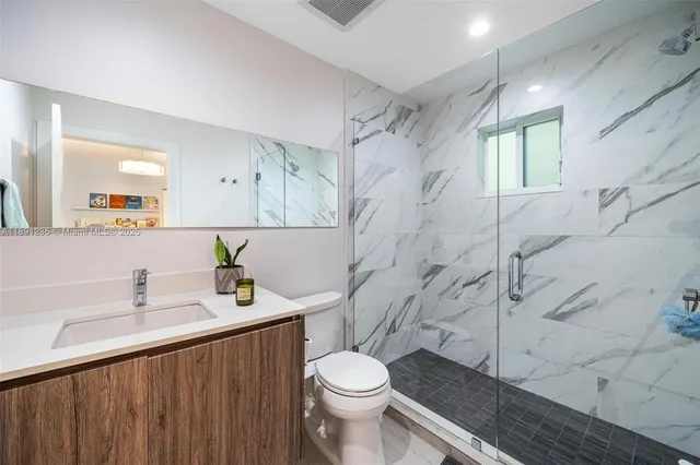 a bathroom with a sink toilet vanity and shower