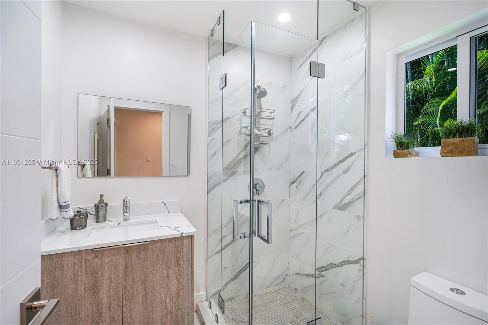 2437 Southwest 25th Terrace Miami, FL 33133 - Photo 32 of 32 a bathroom with a granite countertop sink a shower and a mirror