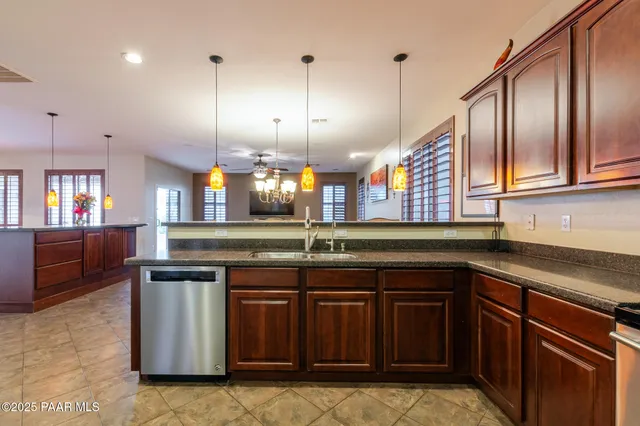 a kitchen with stainless steel appliances granite countertop a sink a stove and a wooden cabinets