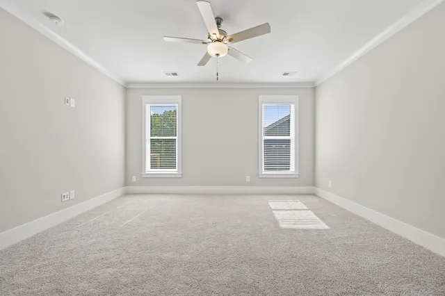 an empty room with windows and ceiling fan