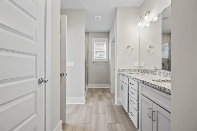 a bathroom with a granite countertop sink two mirror and shower