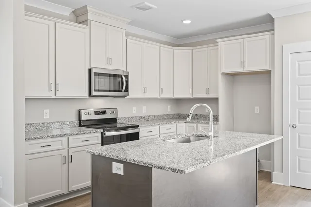 a kitchen with granite countertop a sink a stove and cabinets