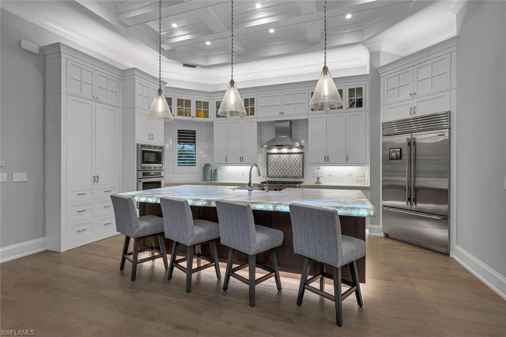 11910 Via Salerno Way Miromar Lakes, FL 33913 - Photo 10 of 50 a kitchen with kitchen island a dining table chairs stainless steel appliances and cabinets