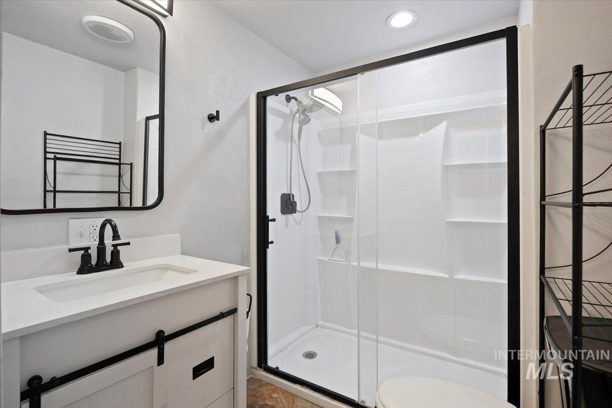 810 South 9th Street Rupert, ID 83350 - Photo 17 of 31 Bathroom featuring vanity, a stall shower, a towel warmer, and a textured wall