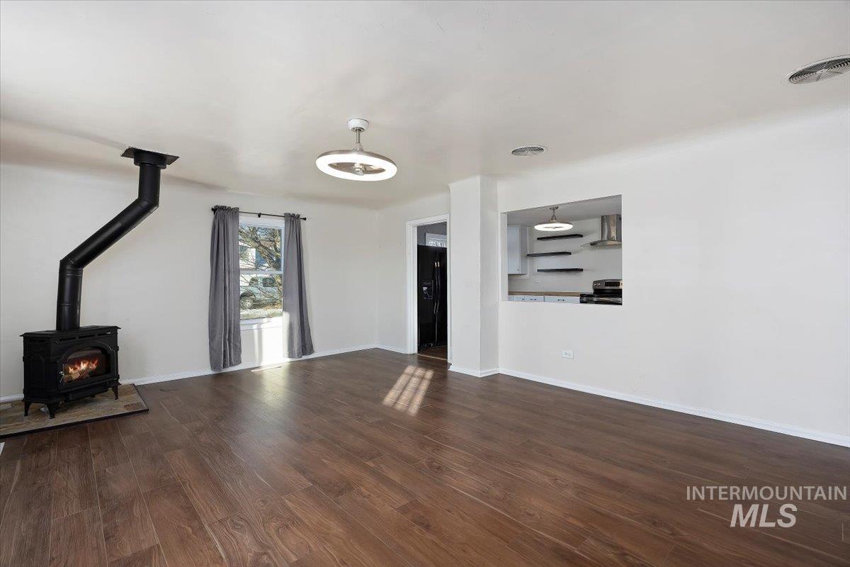 810 South 9th Street Rupert, ID 83350 - Photo 4 of 31 Unfurnished living room with a wood stove and dark wood-style floors