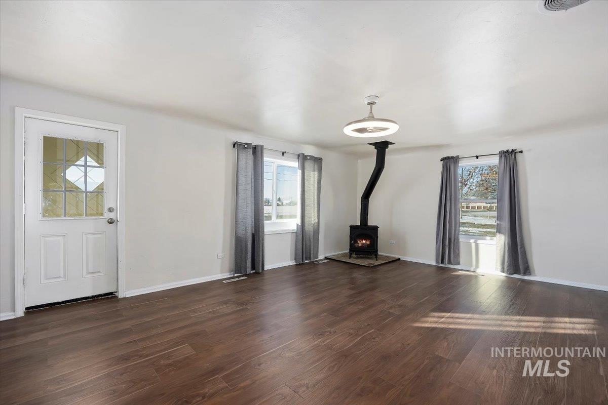 810 South 9th Street Rupert, ID 83350 - Photo 5 of 31 Unfurnished living room with a wood stove and dark wood-style floors