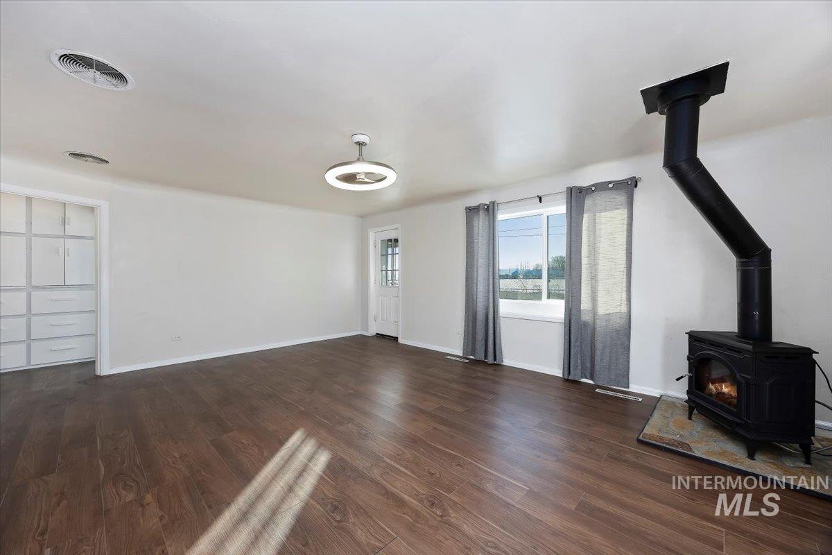 810 South 9th Street Rupert, ID 83350 - Photo 7 of 31 Unfurnished living room featuring a wood stove and dark wood-style flooring