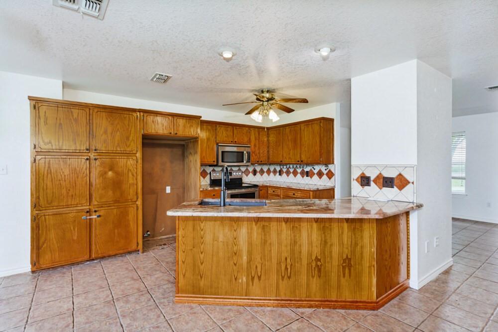 4316 Leona Road Bowie, TX 76230 - Photo 3 of 37 a kitchen with stainless steel appliances granite countertop a refrigerator and a stove