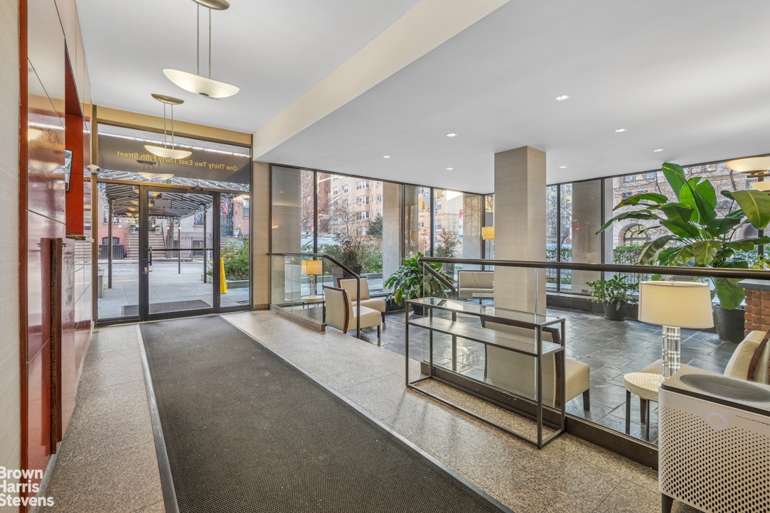 132 East 35th Street, Unit 16F Manhattan, NY 10016 - Photo 12 of 14 a view of a kitchen with kitchen island stainless steel appliances wooden floor and a large window