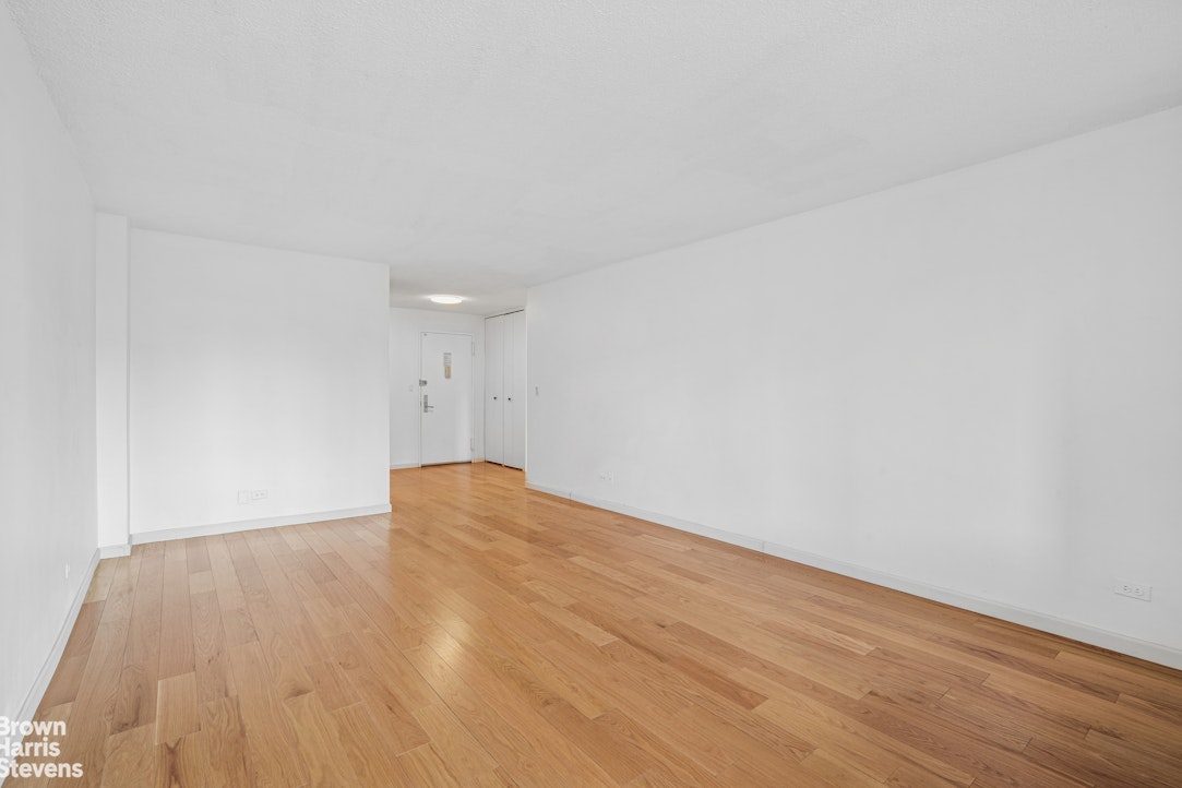 132 East 35th Street, Unit 16F Manhattan, NY 10016 - Photo 4 of 14 a view of empty room with wooden floor and fan