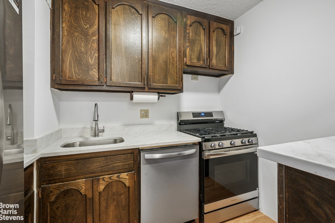 132 East 35th Street, Unit 16F Manhattan, NY 10016 - Photo 5 of 14 a kitchen with stainless steel appliances granite countertop a stove a sink and a microwave