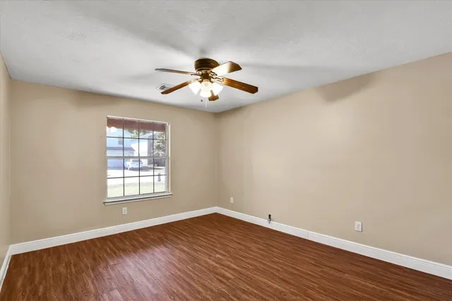 a view of an empty room with wooden floor and a window