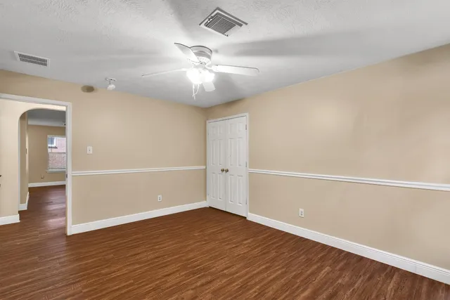 an empty room with wooden floor and ceiling fan