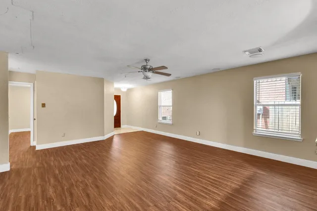 an empty room with wooden floor and windows