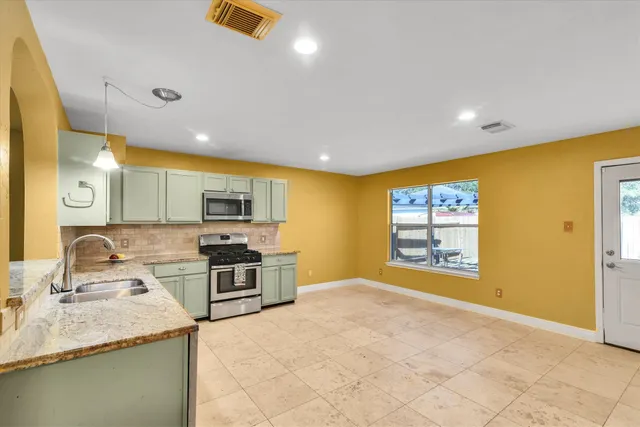 a kitchen with stainless steel appliances granite countertop a sink and a stove next to a window