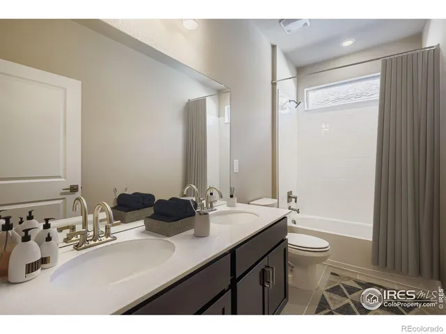 a bathroom with a double vanity sink toilet mirror and bathtub