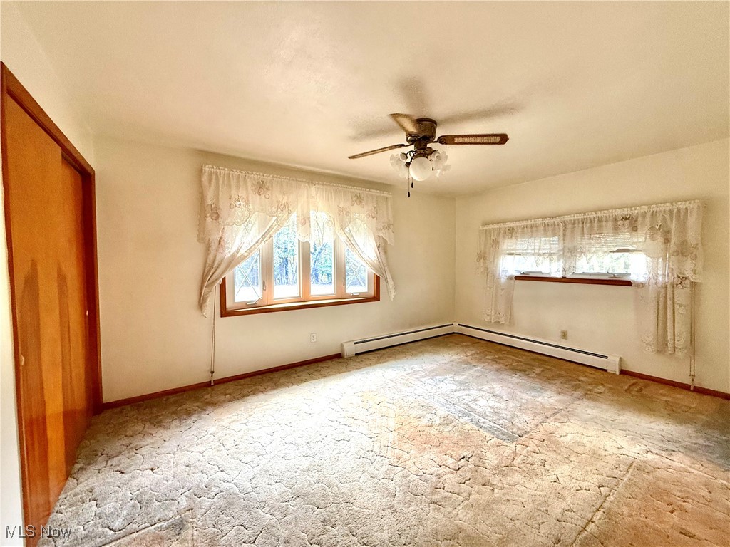 4878 Wylie Ridge Road New Cumberland, WV 26047 - Photo 8 of 20 Unfurnished bedroom with a ceiling fan, a closet, baseboard heating, and light colored carpet