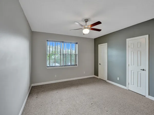 an empty room with windows and fan