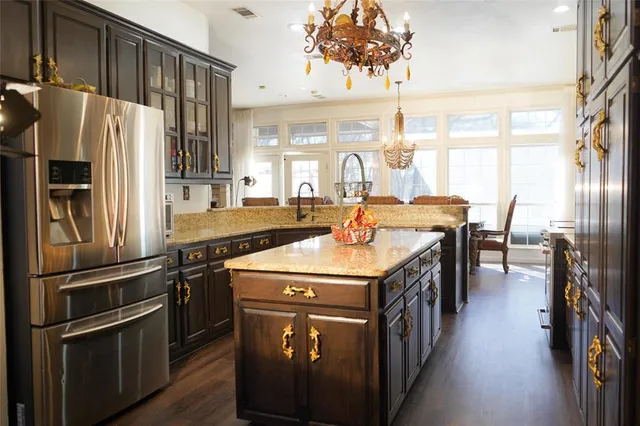 a kitchen with stainless steel appliances granite countertop a refrigerator a stove a sink and a dining table with wooden floor