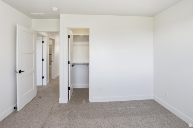 1315 West 3200 South, Unit 17 Perry, UT 84302 - Photo 44 of 58 Bedroom featuring neutral-toned carpeting, white walls, and a built-in closet with shelving and hanging rods