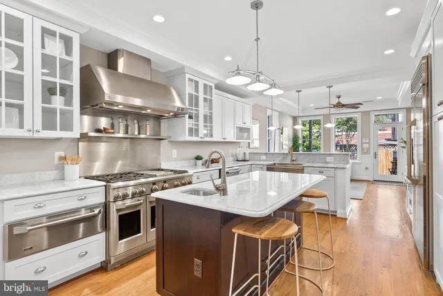 a kitchen with a stove a sink a refrigerator and chairs