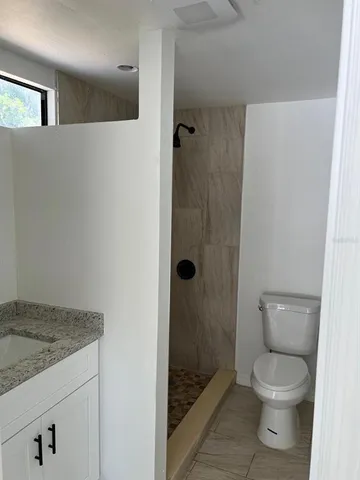a bathroom with a granite countertop toilet and a sink