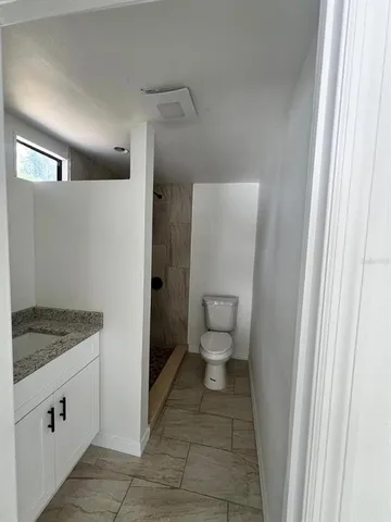 a bathroom with a granite countertop sink and a toilet