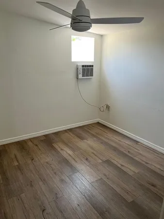 a view of an empty room with wooden floor and windows