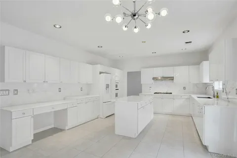a large white kitchen with lots of counter space and view living room
