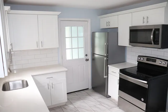 a kitchen with white cabinets and stainless steel appliances