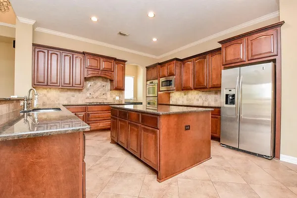 a kitchen with stainless steel appliances granite countertop a sink stove refrigerator and cabinets