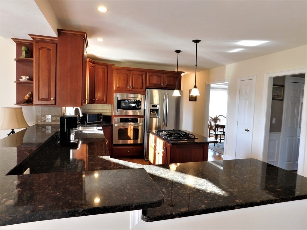 16 Pierce Road Sutton, MA 01590 - Photo 3 of 42 a kitchen with kitchen island granite countertop a stove a refrigerator a sink a dining table and chairs with wooden floor