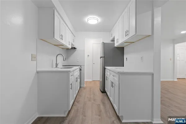 a kitchen with white cabinets and sink