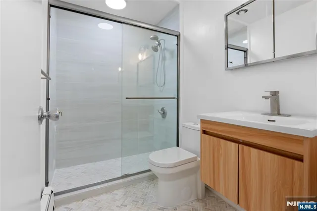 a bathroom with a shower sink vanity and toilet