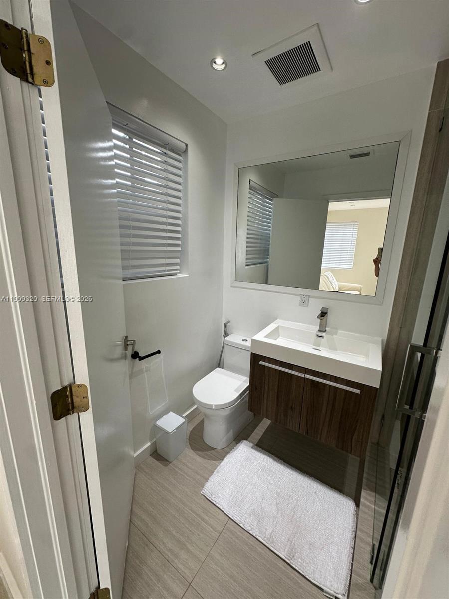 9464 Abbott Avenue Surfside, FL 33154 - Photo 14 of 37 a bathroom with a toilet sink and mirror