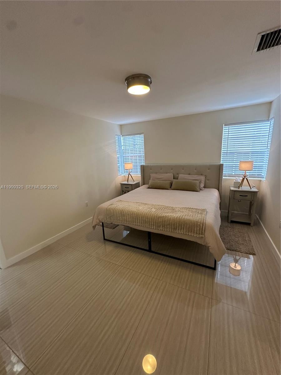 9464 Abbott Avenue Surfside, FL 33154 - Photo 22 of 37 a bedroom with a bed and a night stand
