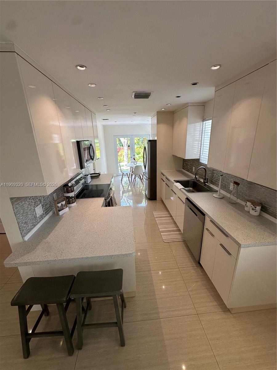 9464 Abbott Avenue Surfside, FL 33154 - Photo 27 of 37 a large white kitchen with cabinets