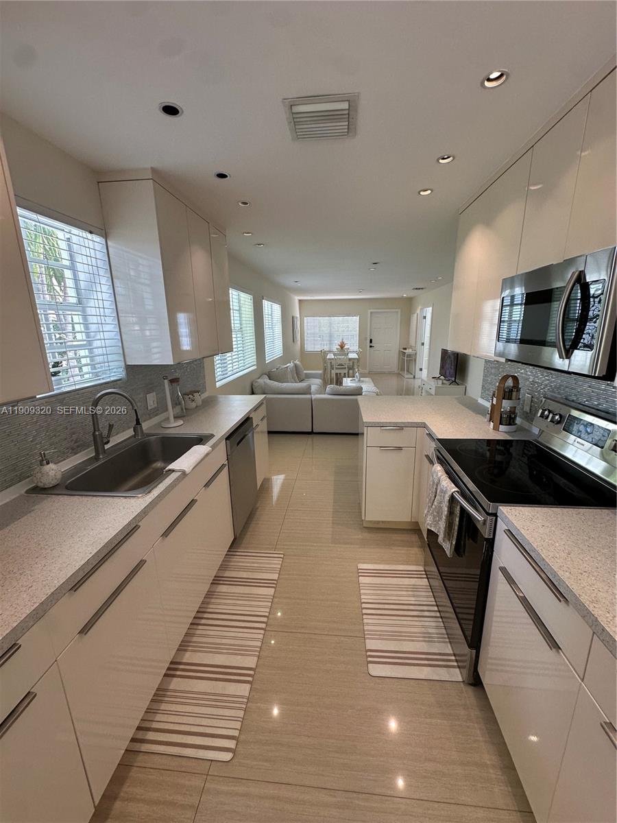 9464 Abbott Avenue Surfside, FL 33154 - Photo 28 of 37 a large kitchen with stainless steel appliances kitchen island granite countertop a sink counter space and a window