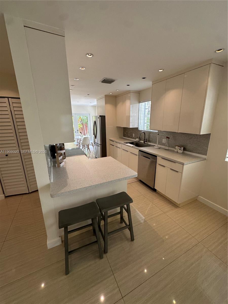 9464 Abbott Avenue Surfside, FL 33154 - Photo 31 of 37 a kitchen with kitchen island a sink table and chairs